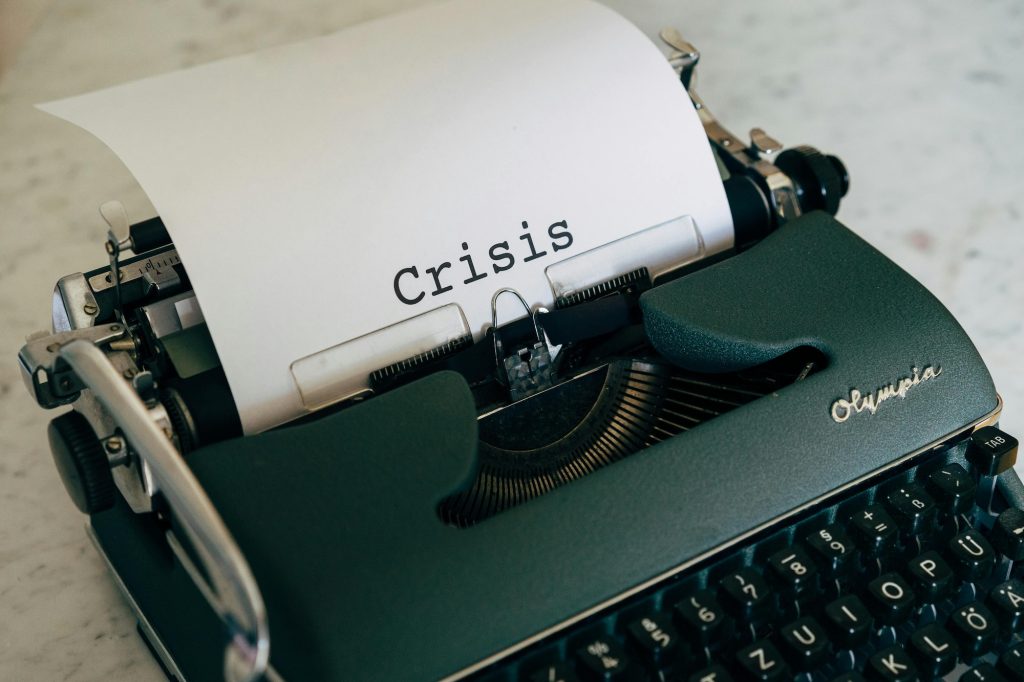 Crisis Intervention green typewriter with the word "crisis" typed on a piece of paper, header for documenting crisis management by Beth Rontal, Documentation Wizard