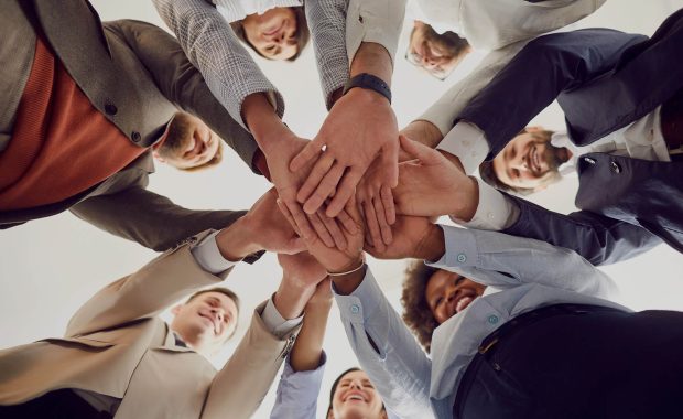 Mental Status Exam Cultural Competency expressed through diverse group in a circle laying hands in the middle